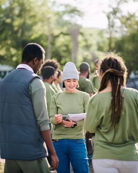 A group of Global Climate Justice Fellows all wearing light green shirts gather in a park