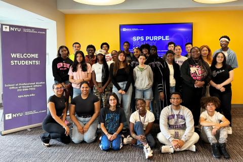 Group of diverse NYU SPS students smiling together in front of a welcome banner and SPS Purple Pantry screen.