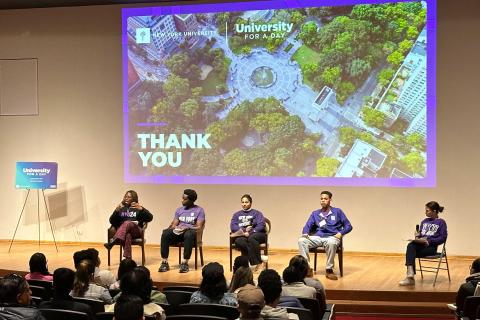 Students speak on a panel at NYU's "University for a Day" event, with an audience seated in an auditorium.