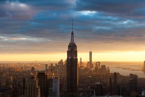 City skyline at sunset with silhouetted skyscrapers and a colorful sky.