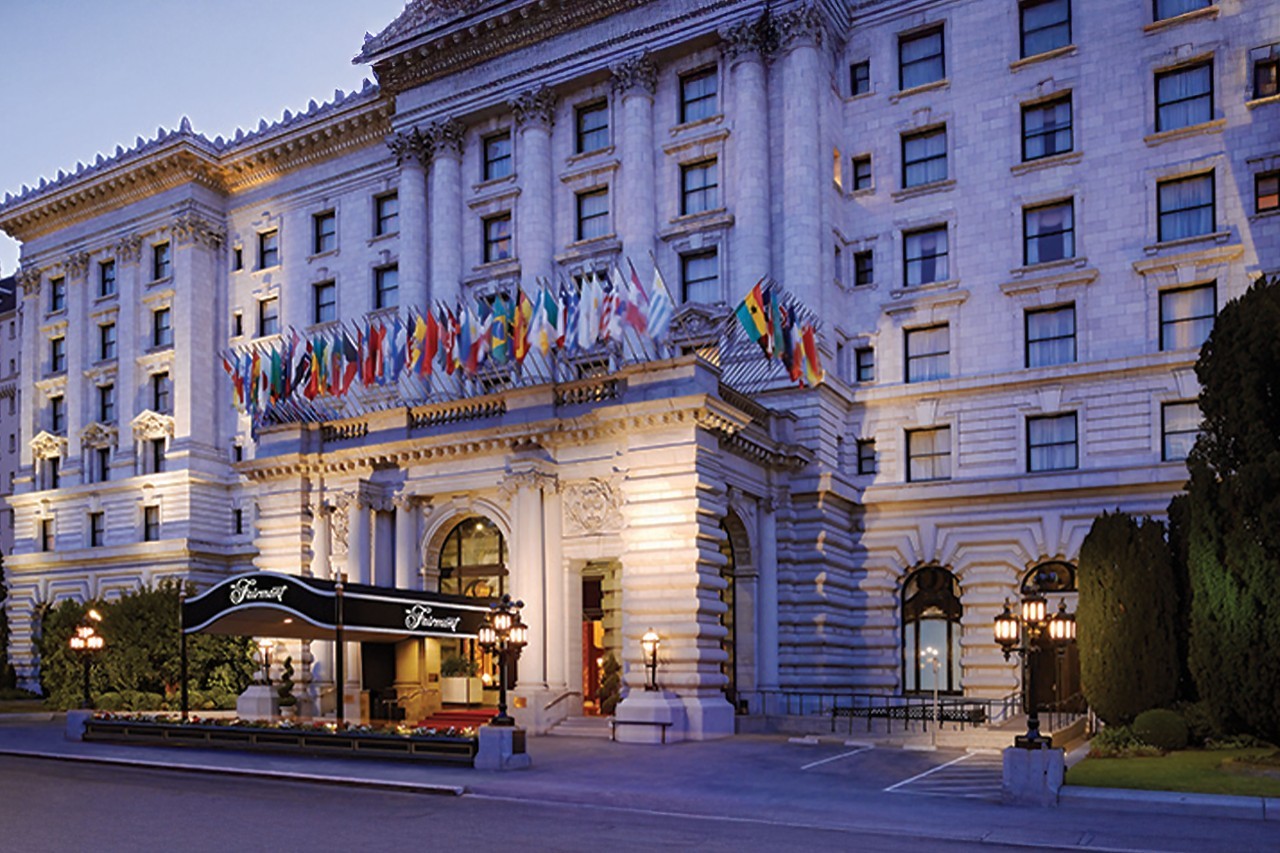 The Fairmont hotel with classic architecture and a row of international flags above its entrance.