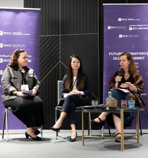 At the Future of Work conference held at NYU SPS, a speaker gives a presentation on stage in front of a large group of attendees