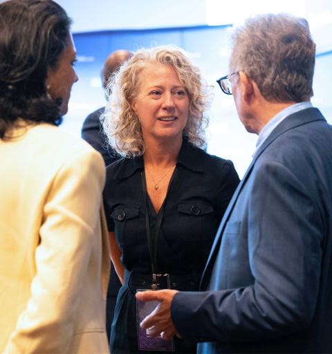 Three people engage in a conversation at a networking event.