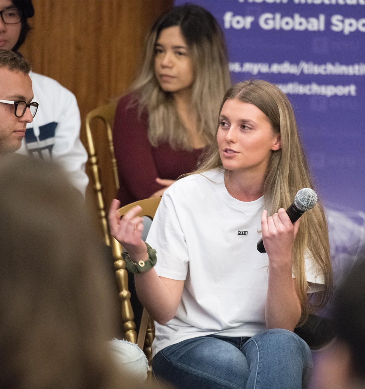 A young female audience member asks a question during a panel discussion about global sports at NYU SPS.