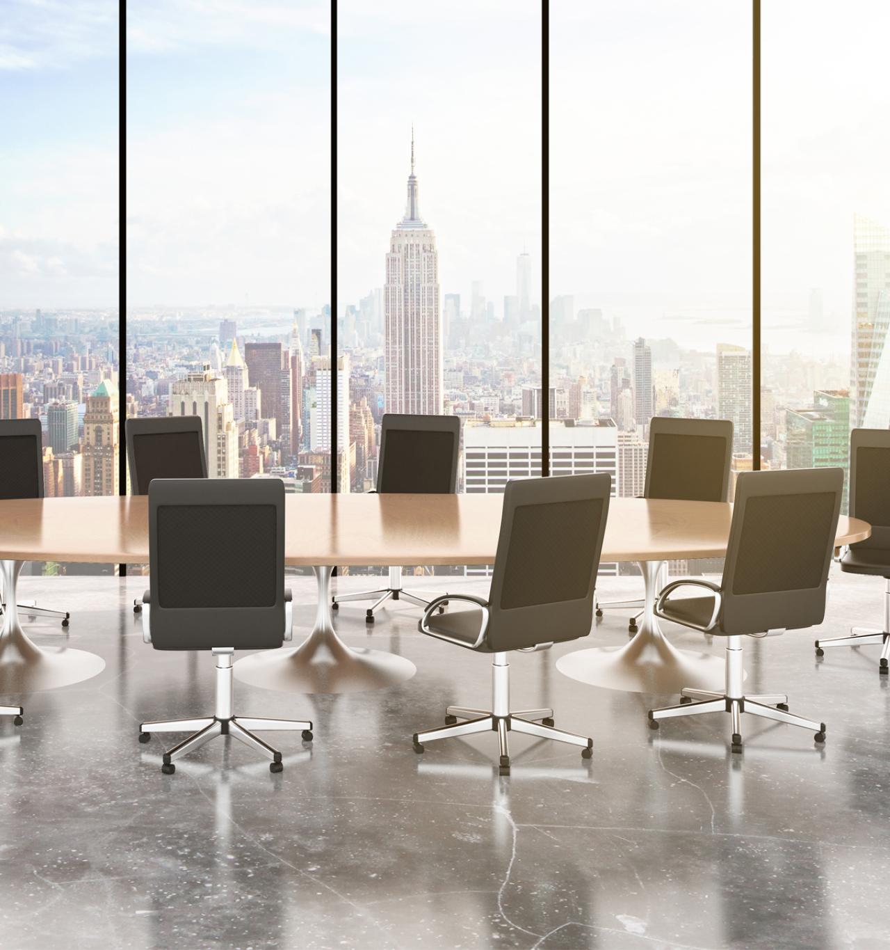 An empty boardroom overlooks midtown Manhattan through floor-to-ceiling windows.