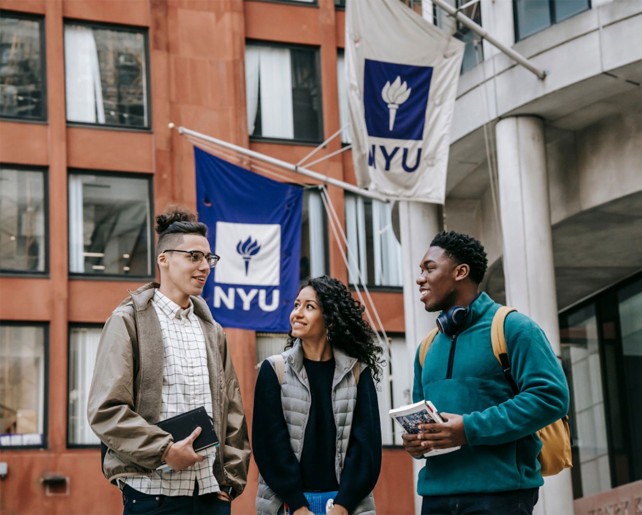 3 students in front of one of NYU's buildings