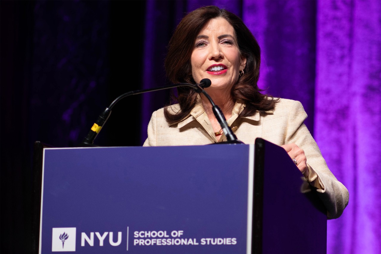 Kathy Hochul speaks at a lectern at the Capital Markets in Real Estate Conference at NYU SPS.