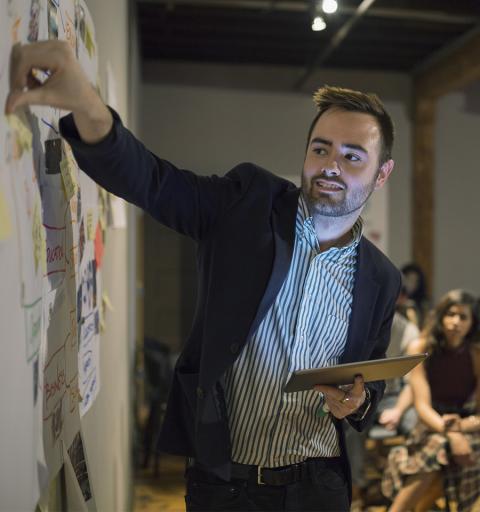 Man adjusting notes on white board holding tablet