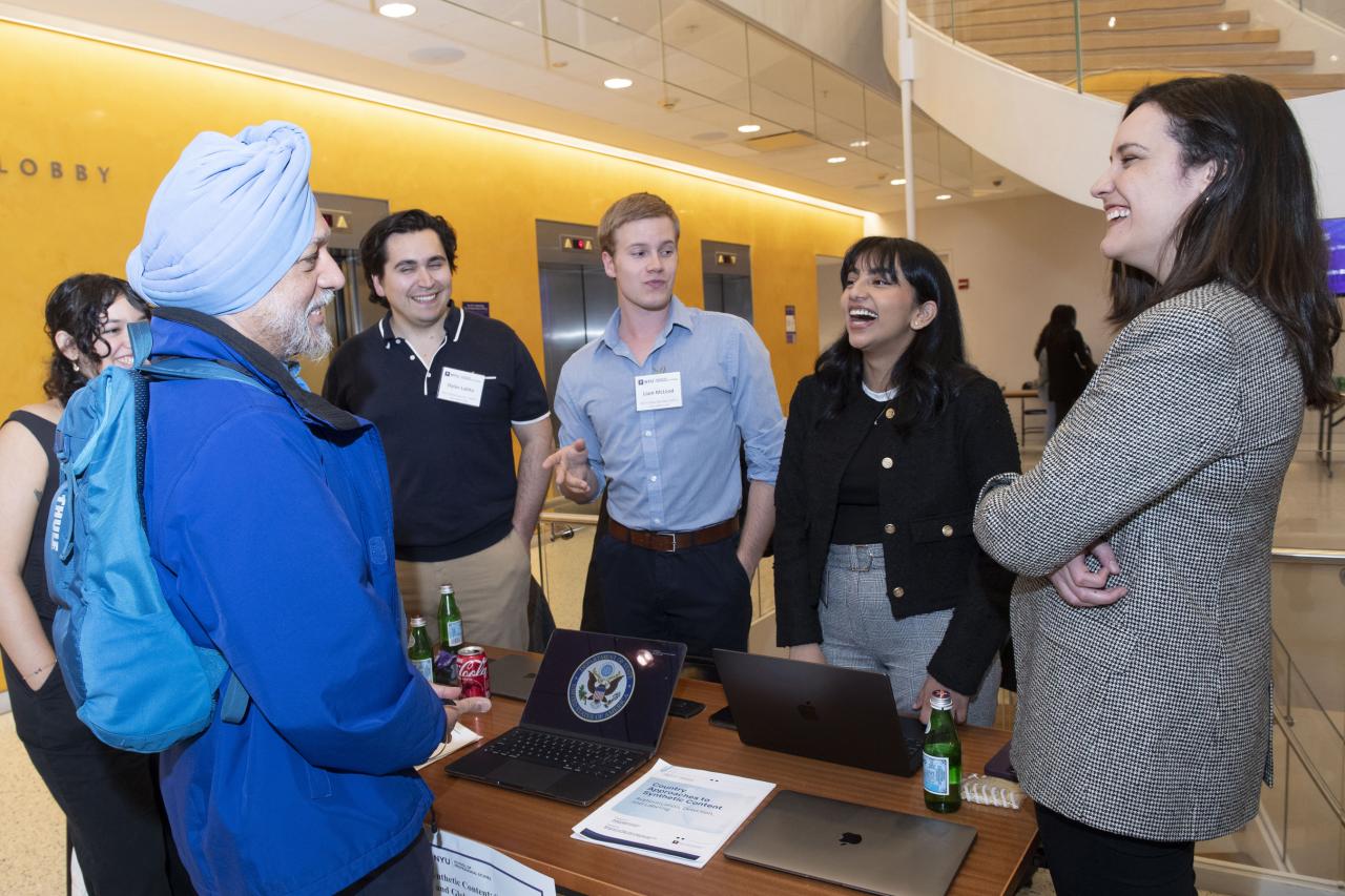 Six people stand around a table and discuss Navigating Synthetic Content at NYU SPS's Center for Global Affairs.