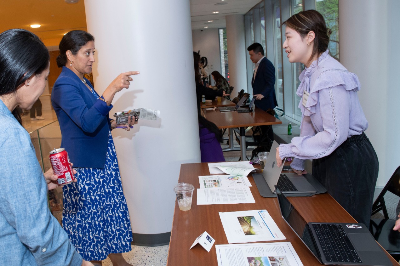 An NYU SPS student shares her capstone project with faculty at a Capstone fair.