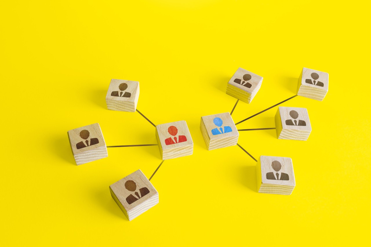 Wooden blocks representing team leaders connected across a yellow background.