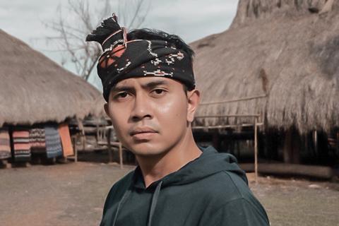 Indonesian man in a headdress poses for a photo representing Sobat Boland Empower Sustinable Rural Tourism Destination in Indonesia