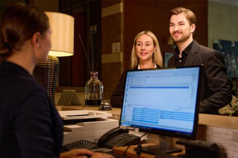Smiling-couple-standing-at-reception-hotel-desk