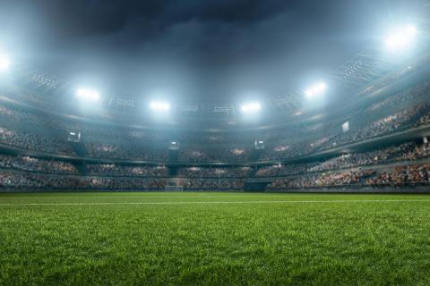 Brightly lit soccer stadium filled with people in the audience.