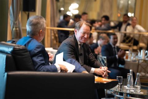 Two men converse on stage.