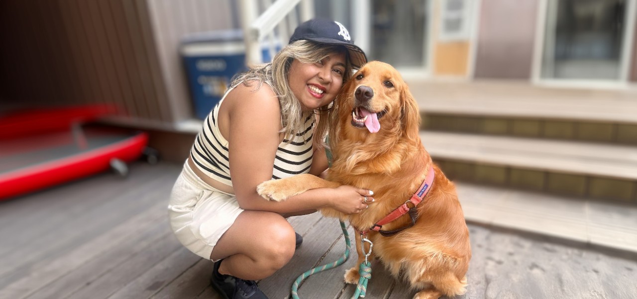 Bhavana Singh, Division of Programs in Business at NYU SPS alumnus, smiles for the camera while embracing her golden retriever.