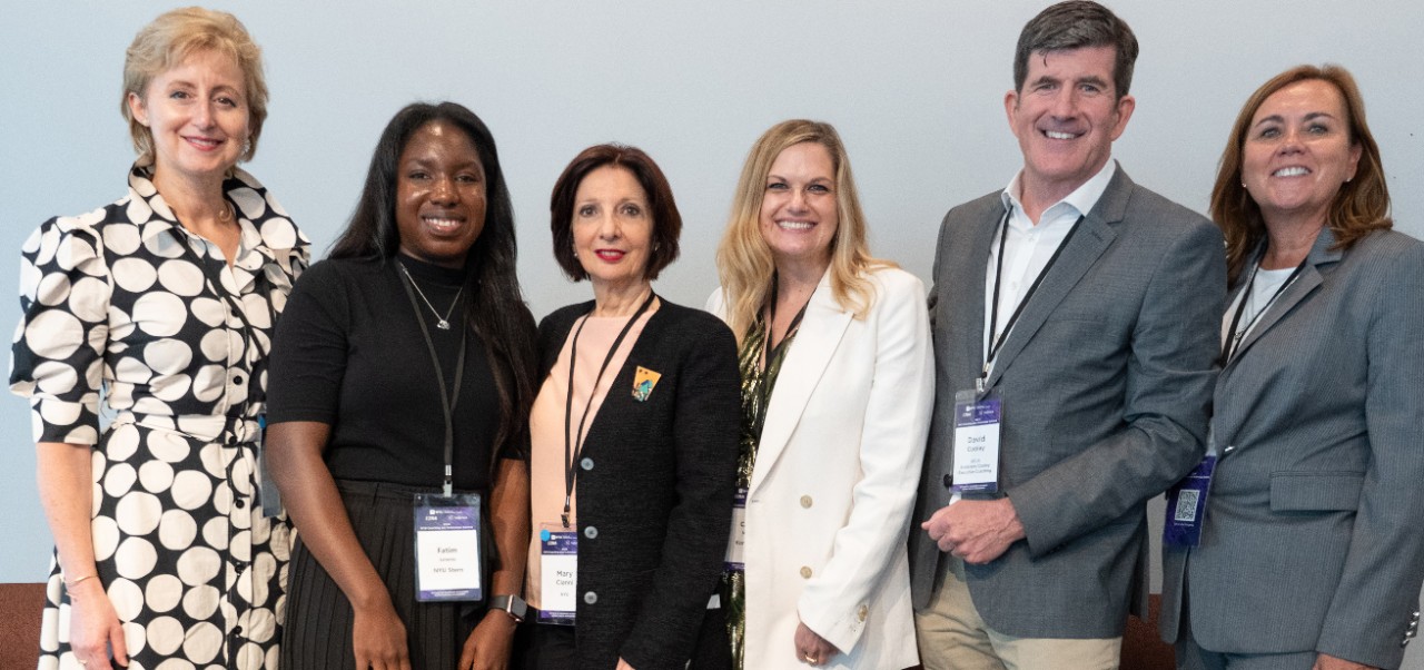 Cathy Merritt, Division of Programs at NYU SPS alumnus, poses for a photo while standing alongside a group of five colleagues.