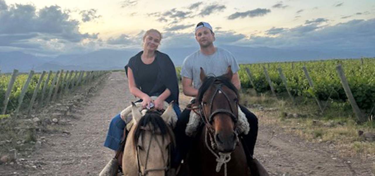 NYU SPS alumnus John Rose and his wife ride horses through a vineyard
