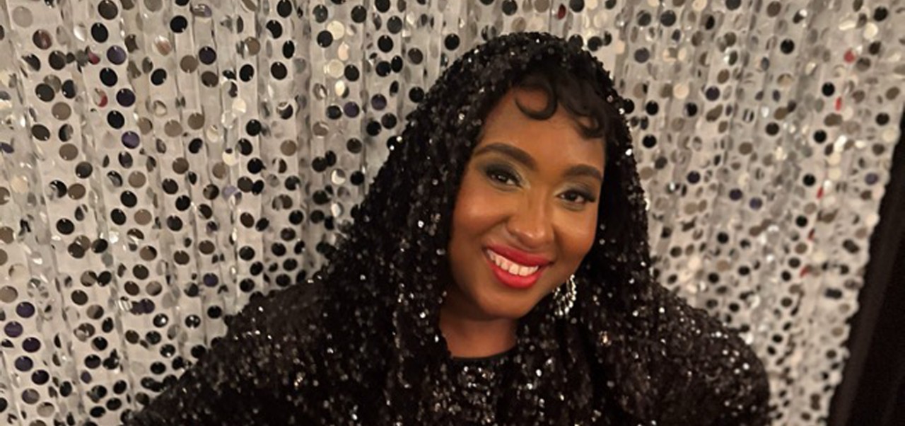 BA in Social Sciences alum Shakia Rose smiles in front of a curtain with silver sequins