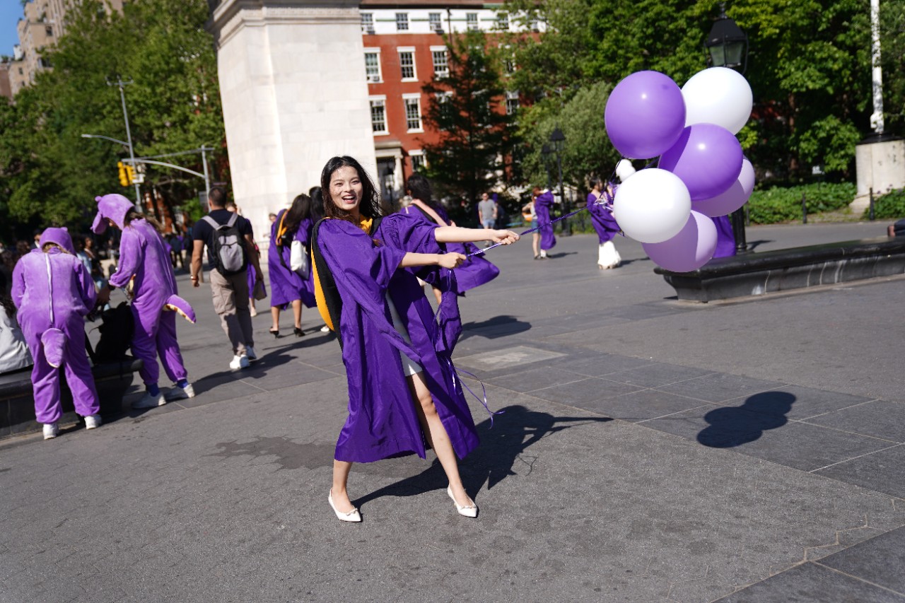 NYU SPS alum celebrates in her graduation gown.
