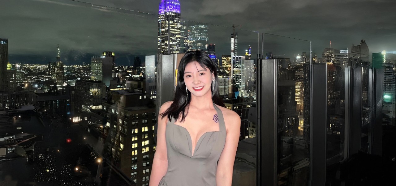Yi Li, Division of Programs in Business at NYU SPS alumnus, poses for a photo on a skydeck at night, with the NYC skyline in the background.