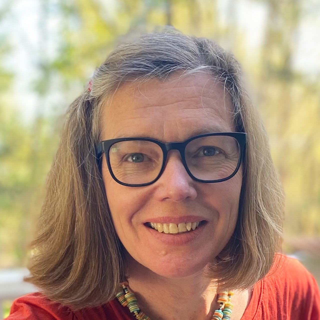 Headshot of Barbara Karsch who wears a red t-shirt with a neutral outdoor background