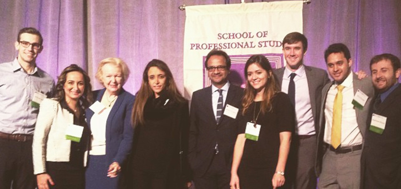 Manish Srivastava, Clinical Professor of Global Real Estate Finance, Investments, and Urban Development at the Schack Institute of Real Estate, NYU SPS, poses for a photo with a group of colleagues and students on a stage.