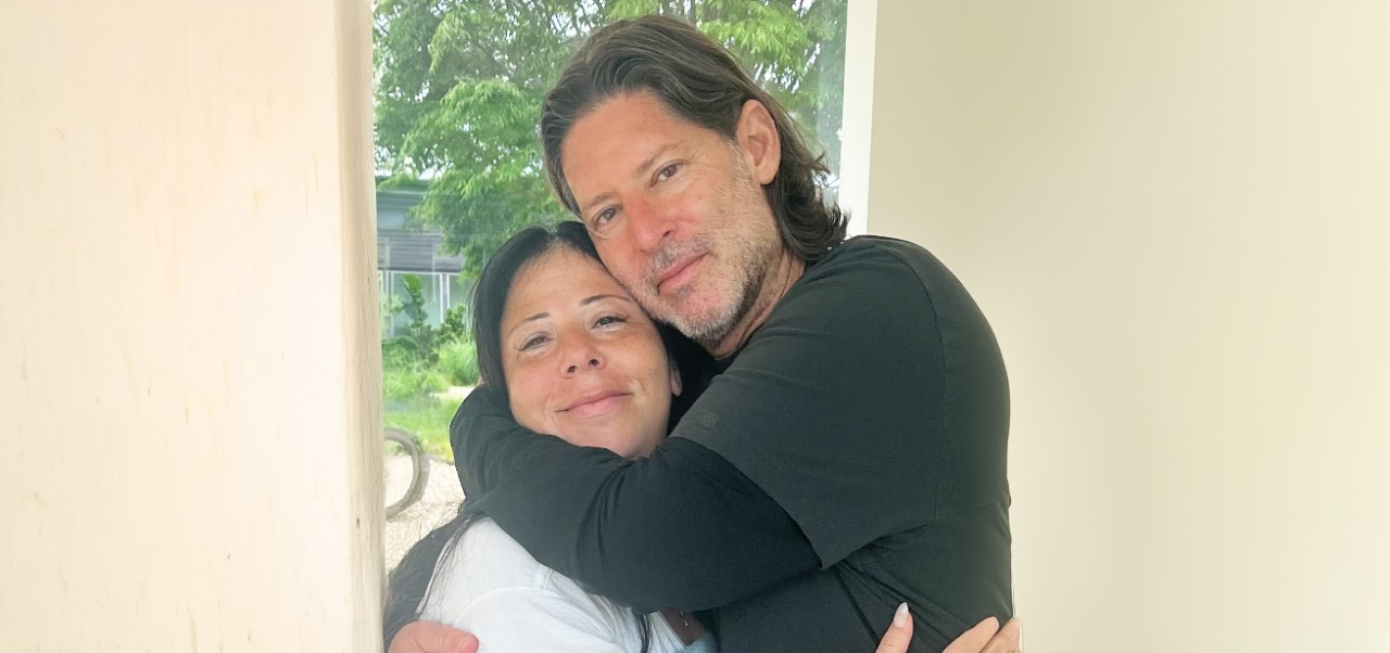 Marc Beckman stands in front of a window while embracing his wife, Alice.
