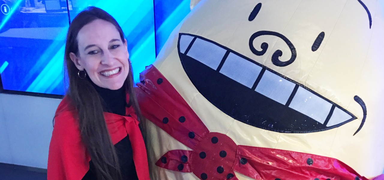 Mindy Stockfield, Adjunct Instructor, Center for Publishing, Writing, and Media at NYU SPS, poses for a photo standing next to an inflatable baby while visiting NASDAQ.