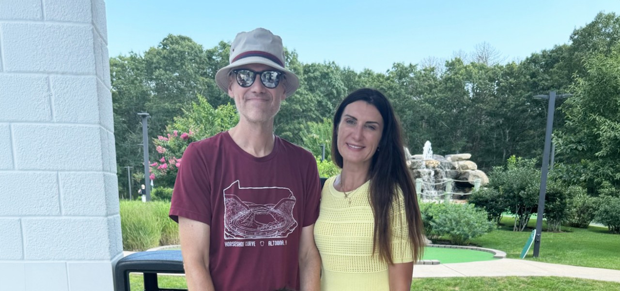 Dr. Steven Goss,  Clinical faculty member and chair of the Management and Technology program in the Division of Programs in Business at NYU SPS, poses for a photo with his wife on a putting green.