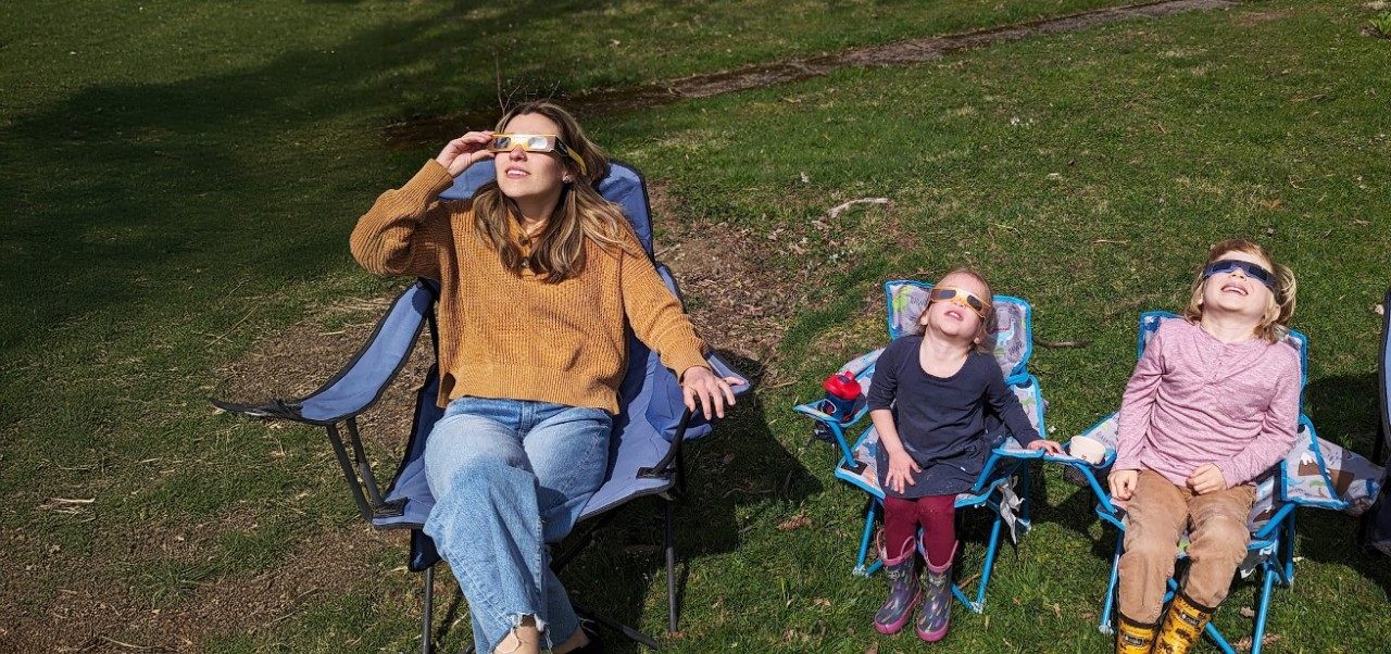 Victoria Chavez-Kruse, Adjunct Instructor, Center for Applied Liberal Arts, NYU SPS views an eclipse in lawn chairs with her two children.