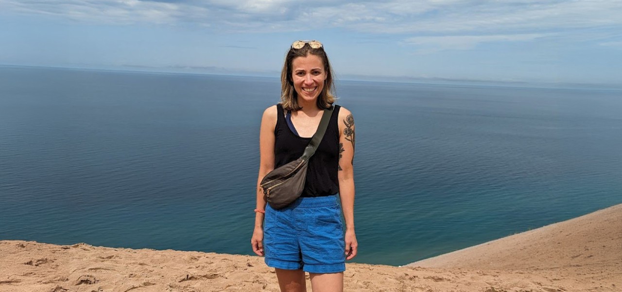 Victoria Chavez-Kruse, Adjunct Instructor, Center for Applied Liberal Arts, NYU SPS, smiles for the camera while standing in front a body of water.