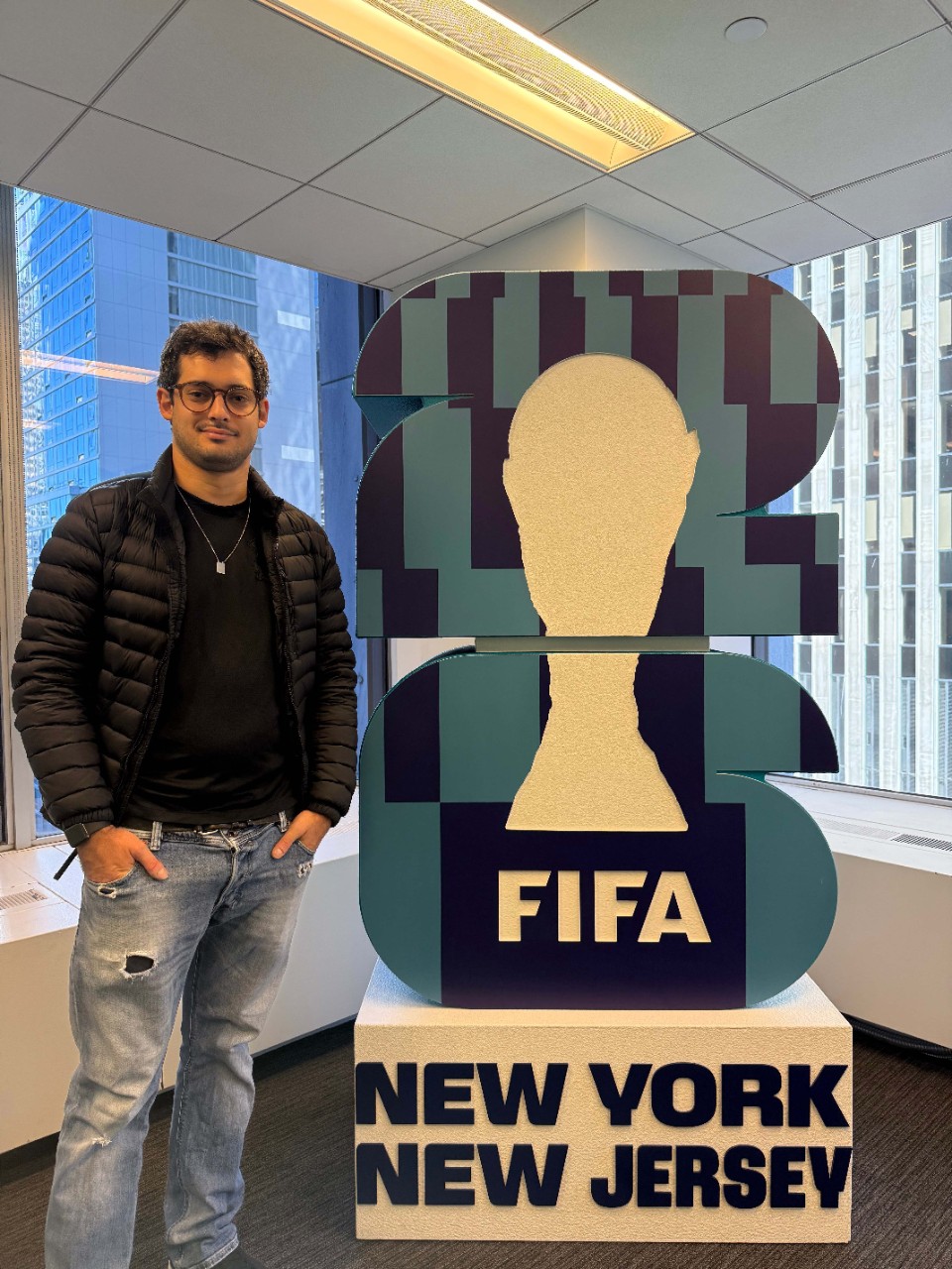 Gustavo Giusti stands beside a FIFA display.