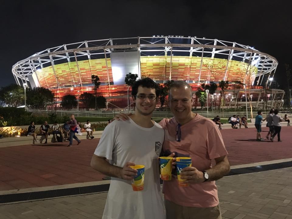 Gustavo Giusti poses for a photo with a friend outside a soccer stadium.