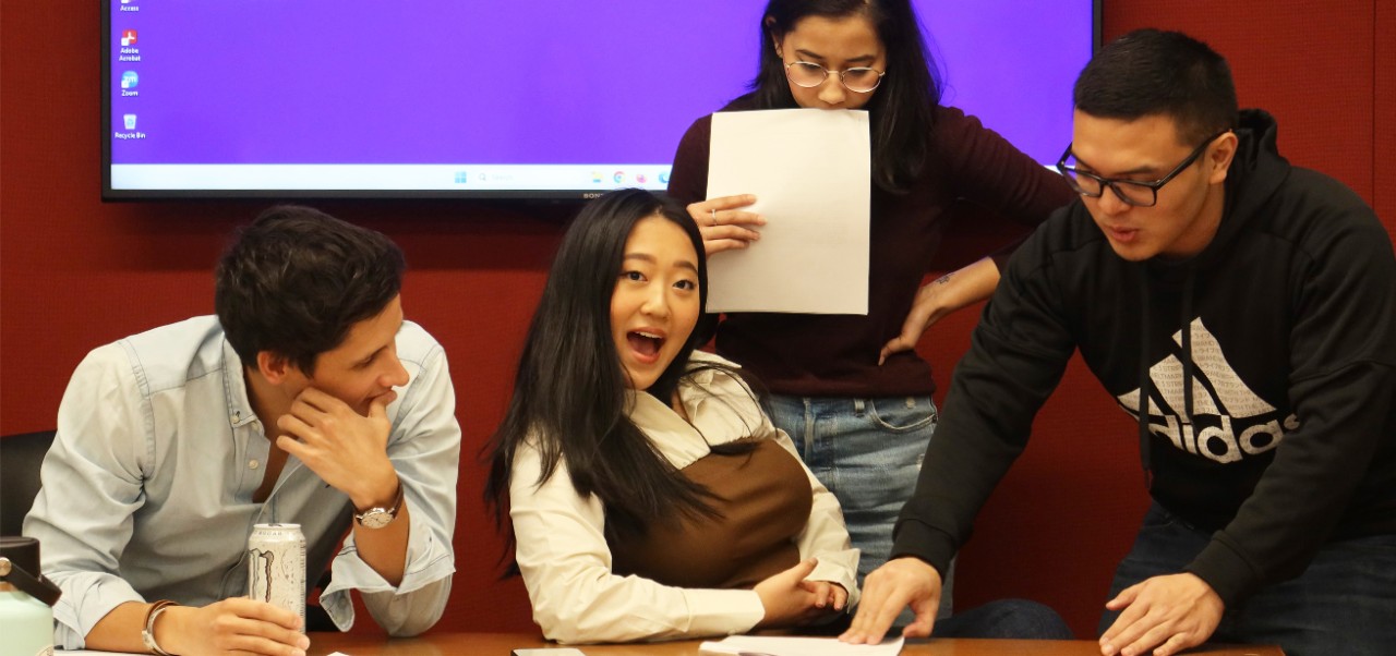 Hannah Choi, student at the Jonathan M. Tisch Center of Hospitality, NYU SPS, makes a funny face while working with students on a project in a classroom.