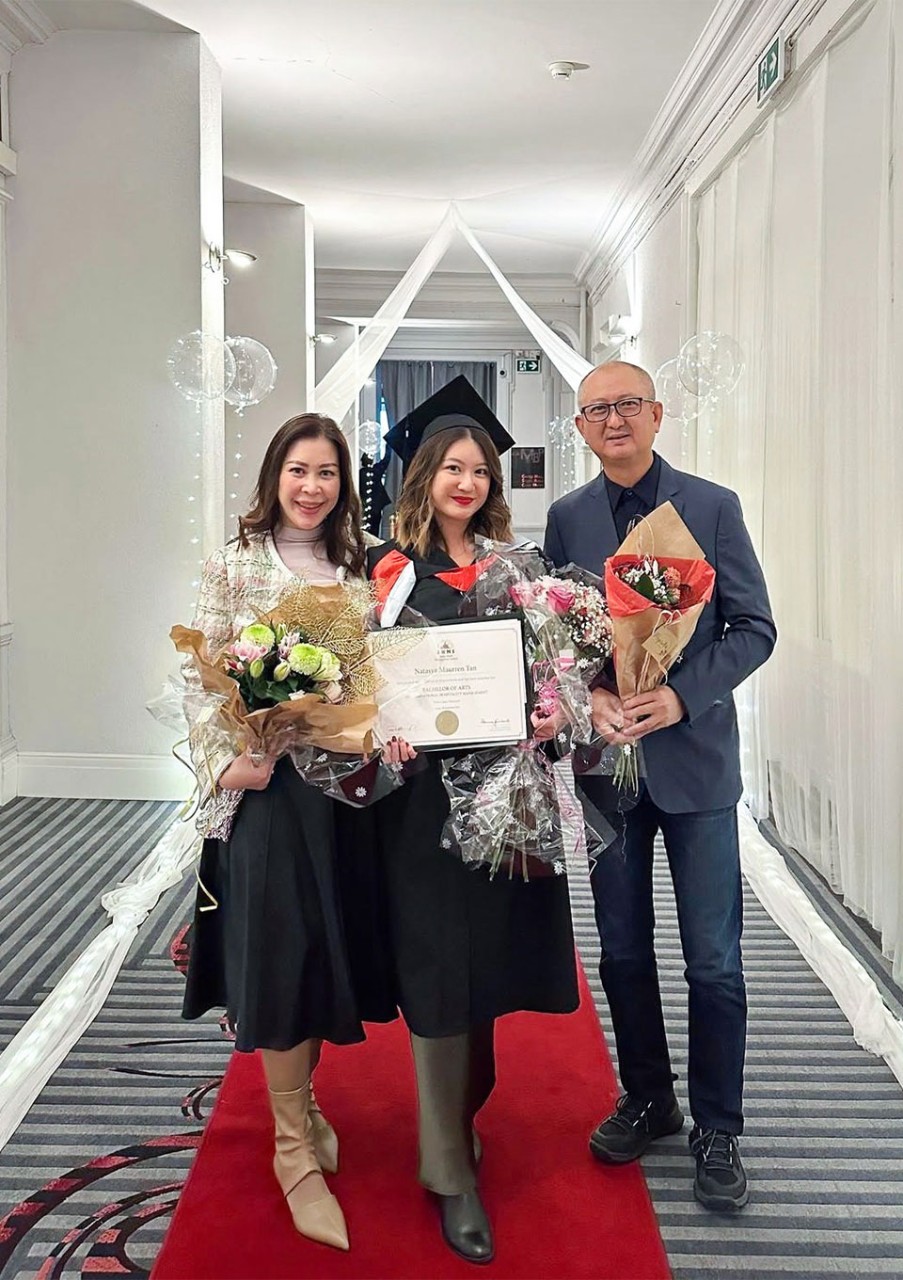 Natasya Maurren Tan poses with her parents, who are holding floral bouquets.