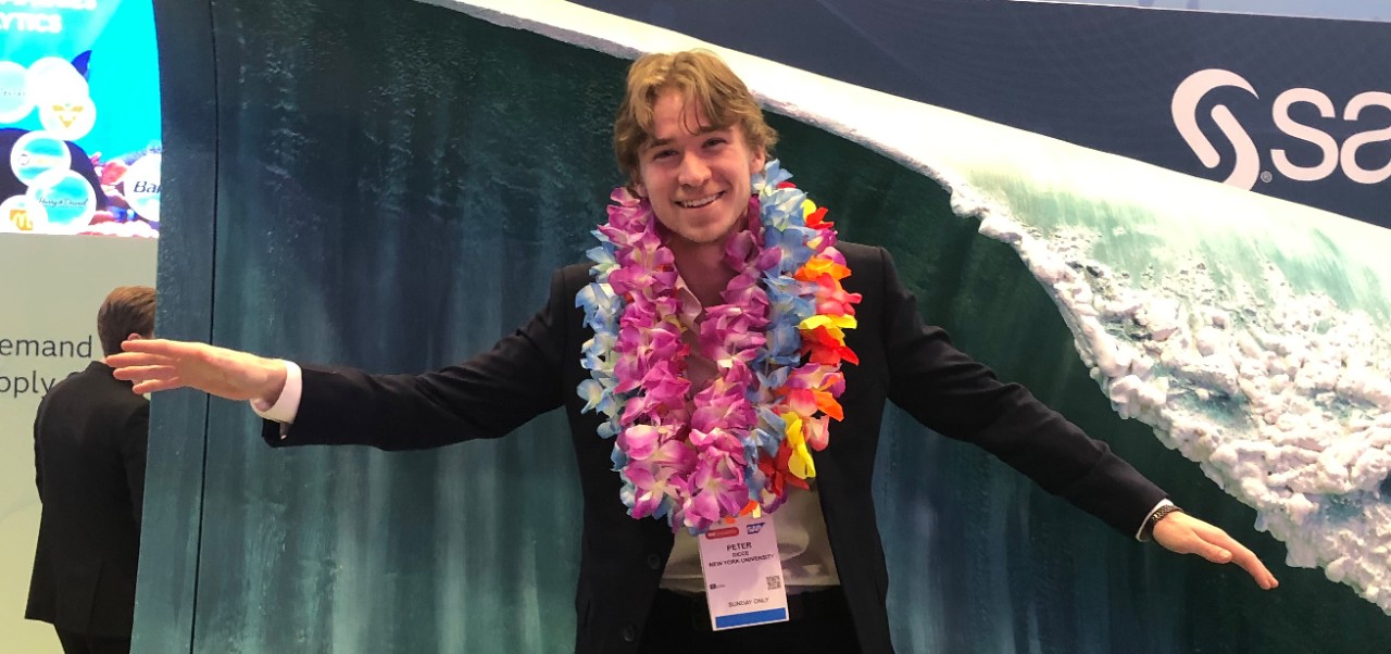 Peter Dicce, student at the Preston Robert Tisch Institute for Global Sport at NYU SPS, poses for a photo while pretending to surf and wearing a number of colorful leis.