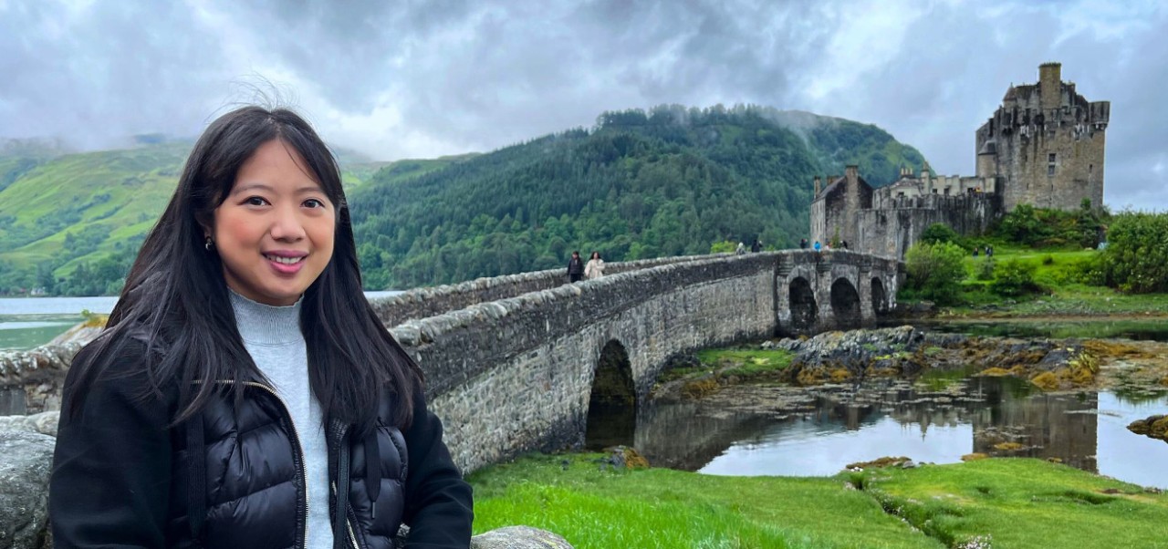 Porsha Seechung, student at the Division of Programs in Business at NYU SPS, smiles for a camera at a castle in the Scottish Highlands.
