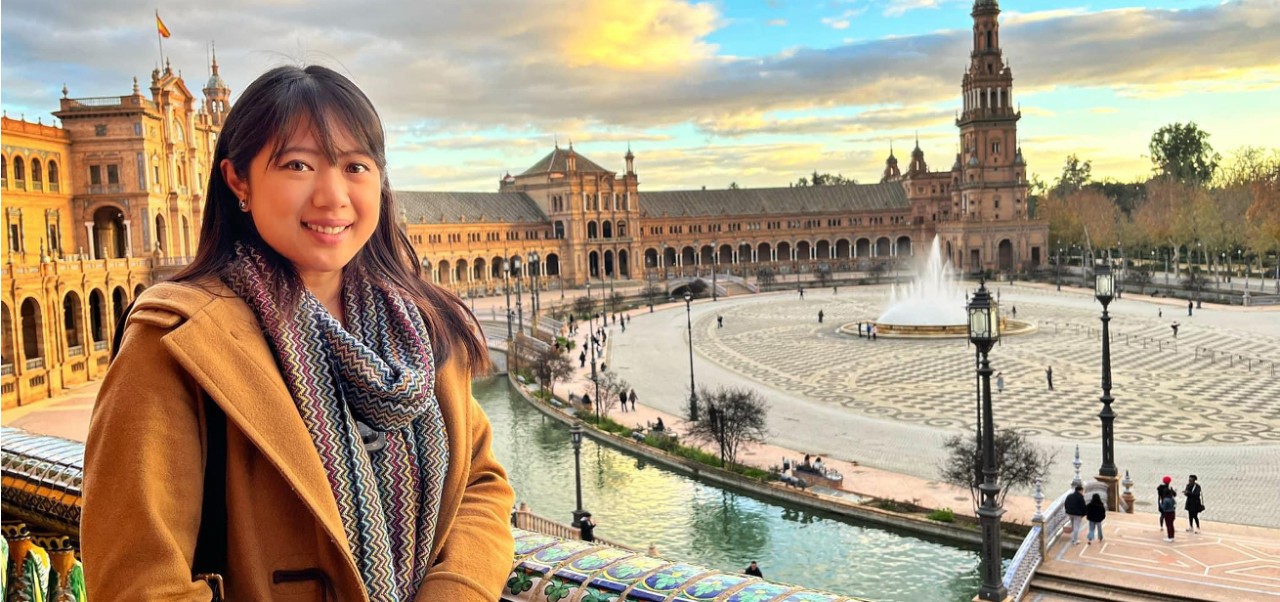 Porsha Seechung, student at the Division of Programs in Business at NYU SPS, smiles for a camera while overlooking a grand town square in Sevilla, Spain.