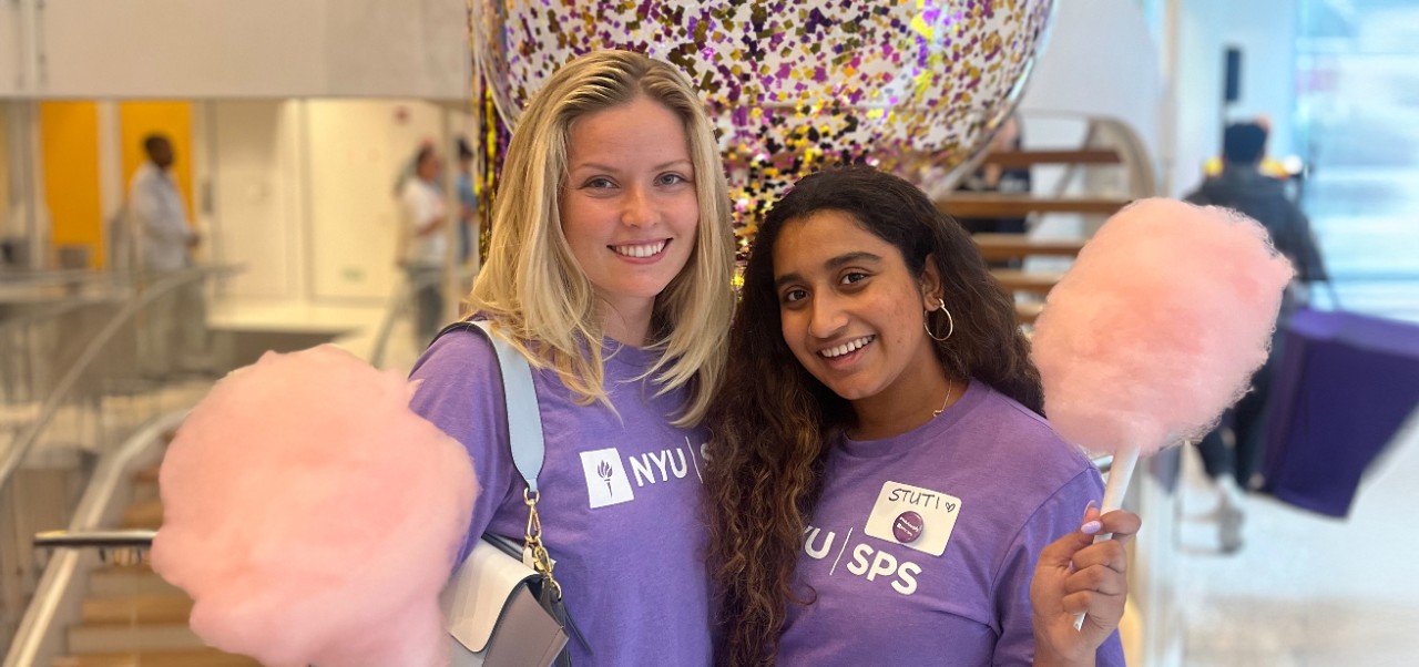 Stuti Daga, student at the Robert Tisch Institute for Global Sport at NYU SPS, smiles for the camera with a friend while holding pink cotton candy.