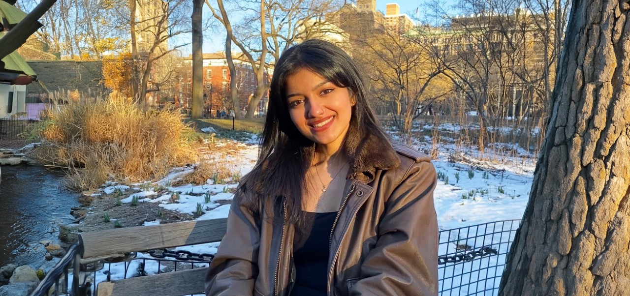 NYU SPS student Surabhi Achar smiles while wearing a purple NYU SPS t-shirt.