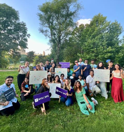 Students hold up signs on a grassy lawn.
