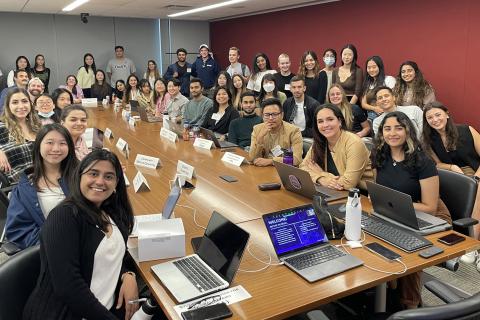Students crowd around a wooden table.