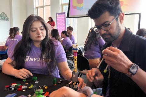 Students sit at a table doing a craft together.