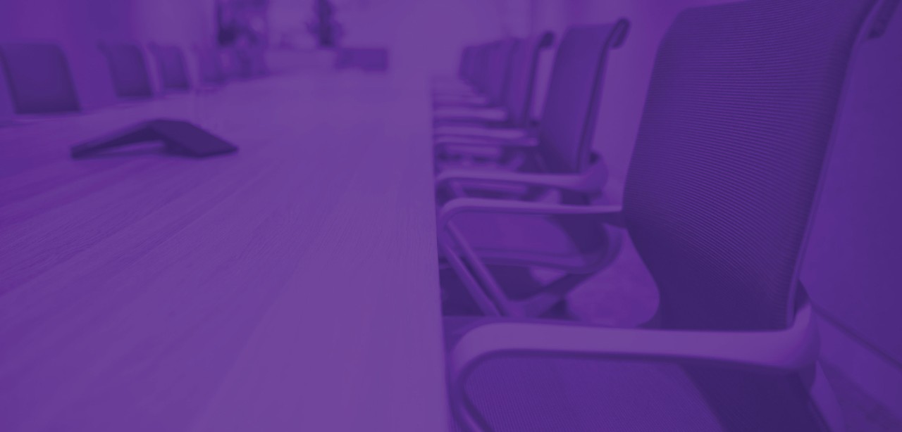 Three colleagues walk down a New York City promenade, passing the window revealing a dimly lit lobby, blurred to suggest motion.