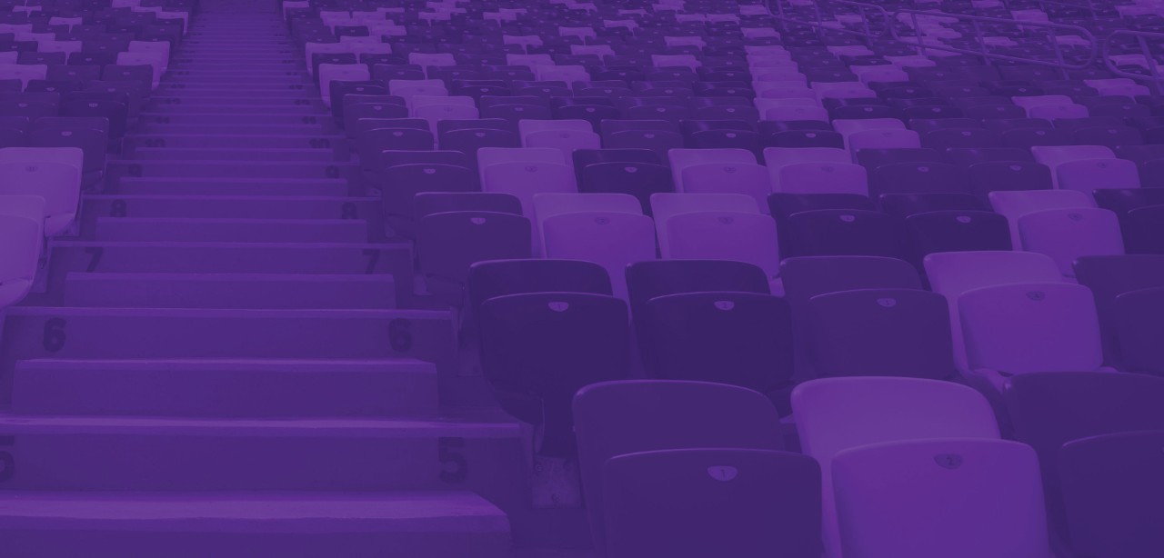 The silhouettes of two men and a woman viewing a major sporting event from a private box.