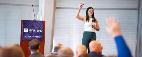 woman raising hand speaking at an event