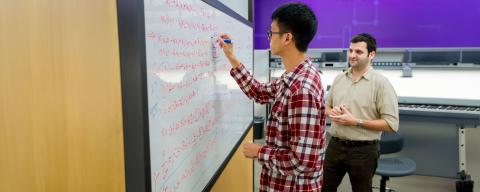 student writing on whiteboard in classroom