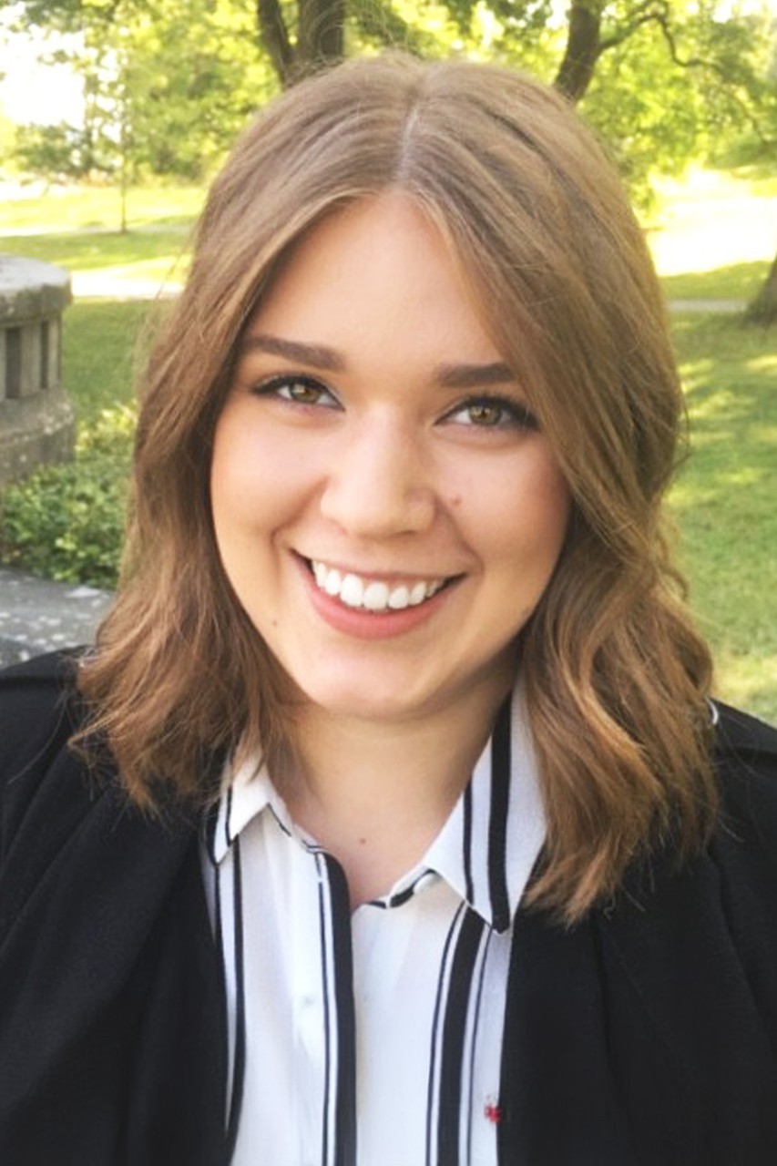 Melanie Stavenow, Center for Global Affairs at NYU SPS alumnus, smiles for the camera dressed in graduation garb.