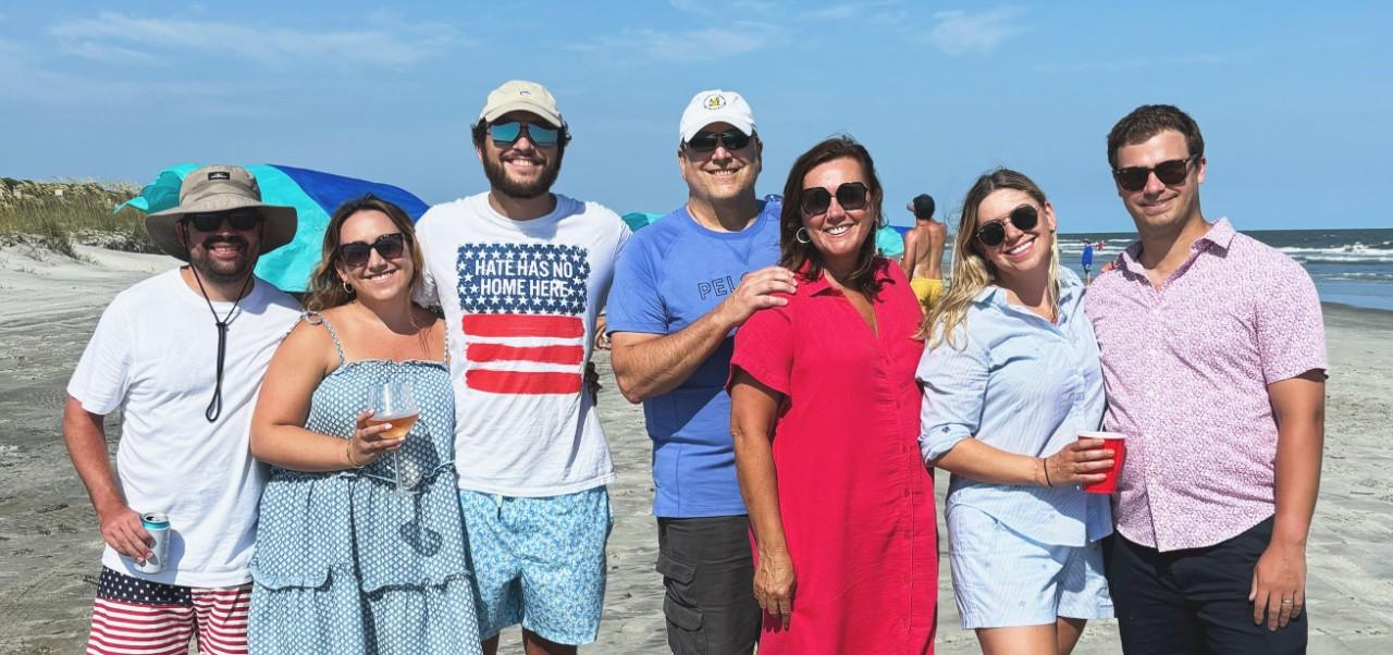NYU SPS Division of Programs in Business alumnus Noreen Beaman poses for a photo with a group of casually dressed family members on a beach.